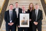 Front row: Shane McCormac (left), Paul McCormac (right), and Conor McCormac holding a photograph of their late father, John. Back row: Ian Jeffers, Commissioner for Victims and Survivors, and Jayne Brady, Head of Civil Service.