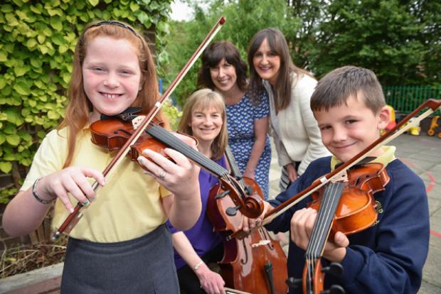 Pupils from Wheatfield PS in North Belfast show off their new skills with Morag Stewart, Principal Cello and facilitator of from the Ulster Orchestra Crescendo project, Maxine Hume, Principal of Wheatfield PS and Linsey Farrell, Programme Director