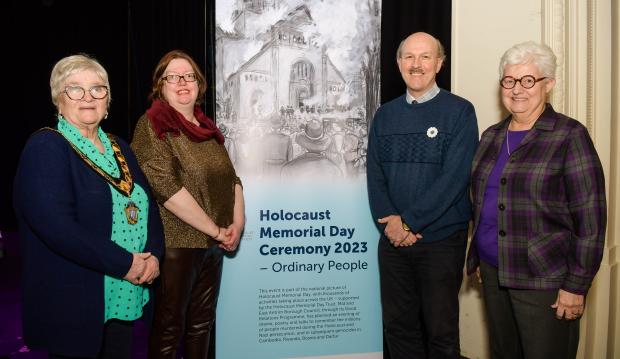 Image of 4 People - standing next to a banner that says Holocaust Memorial Day Ceremony 2023